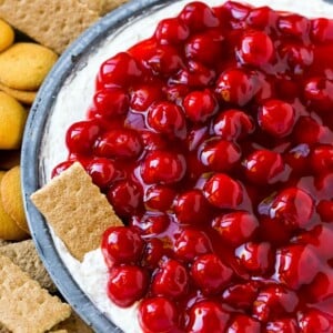 A plate of cherry cheesecake dip with a graham cracker in it.