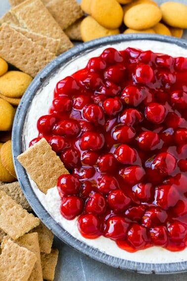 A plate of cherry cheesecake dip with a graham cracker in it.