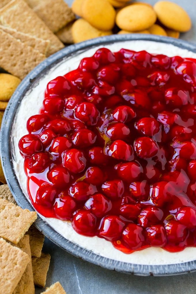 A plate of cherry cheesecake dip surrounded by graham crackers and cookies.