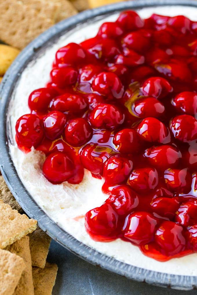 A plate of cherry cheesecake dip with a portion removed.