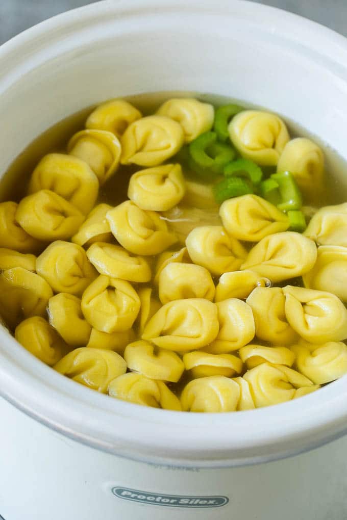 Cheese tortellini in a slow cooker full of soup.