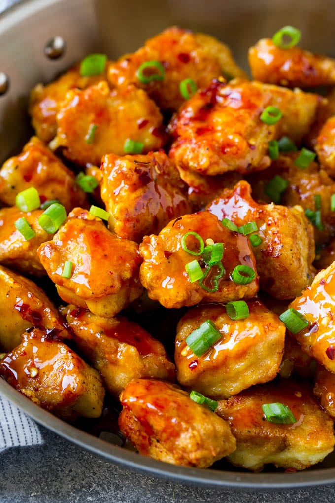 A pan full of crispy firecracker chicken topped with green onions.