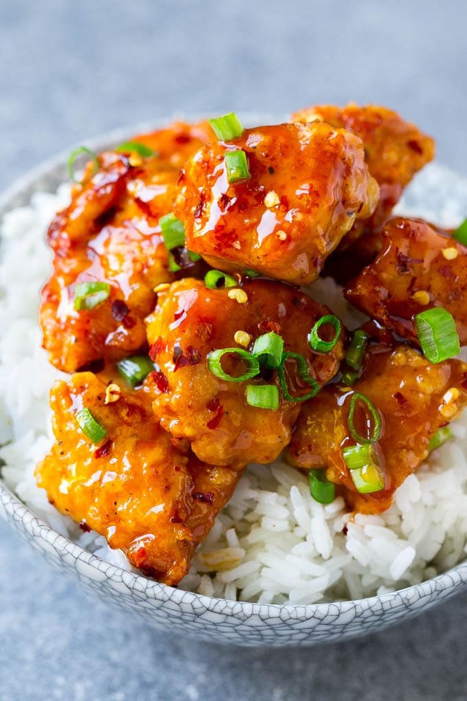 A bowl of rice topped with spicy firecracker chicken.