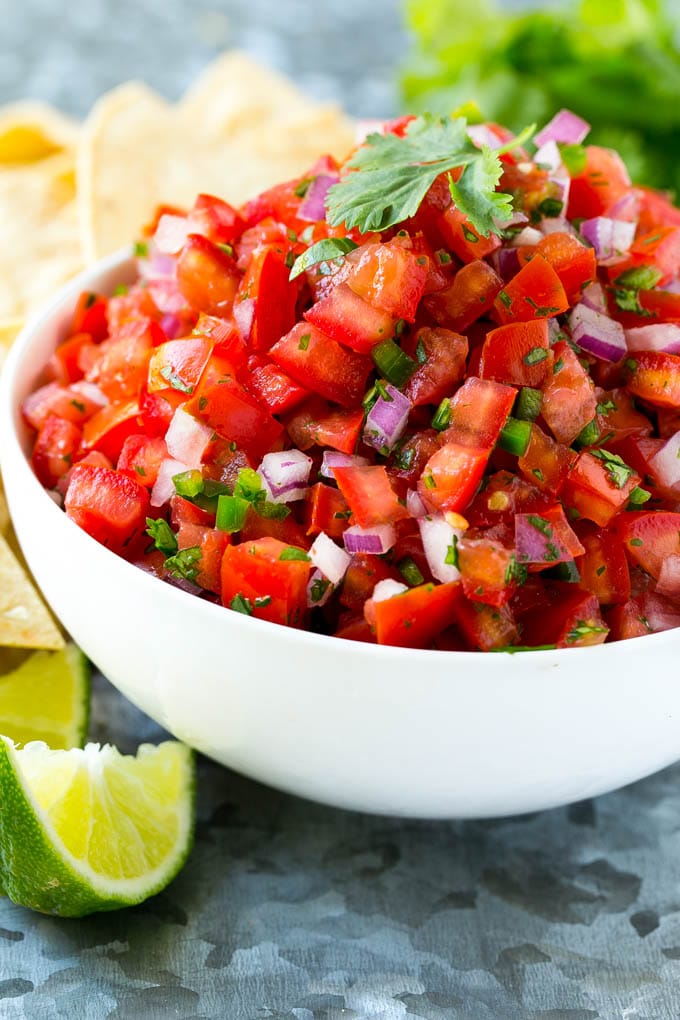 A bowl of homemade pico de gallo surrounded by tortilla chips.