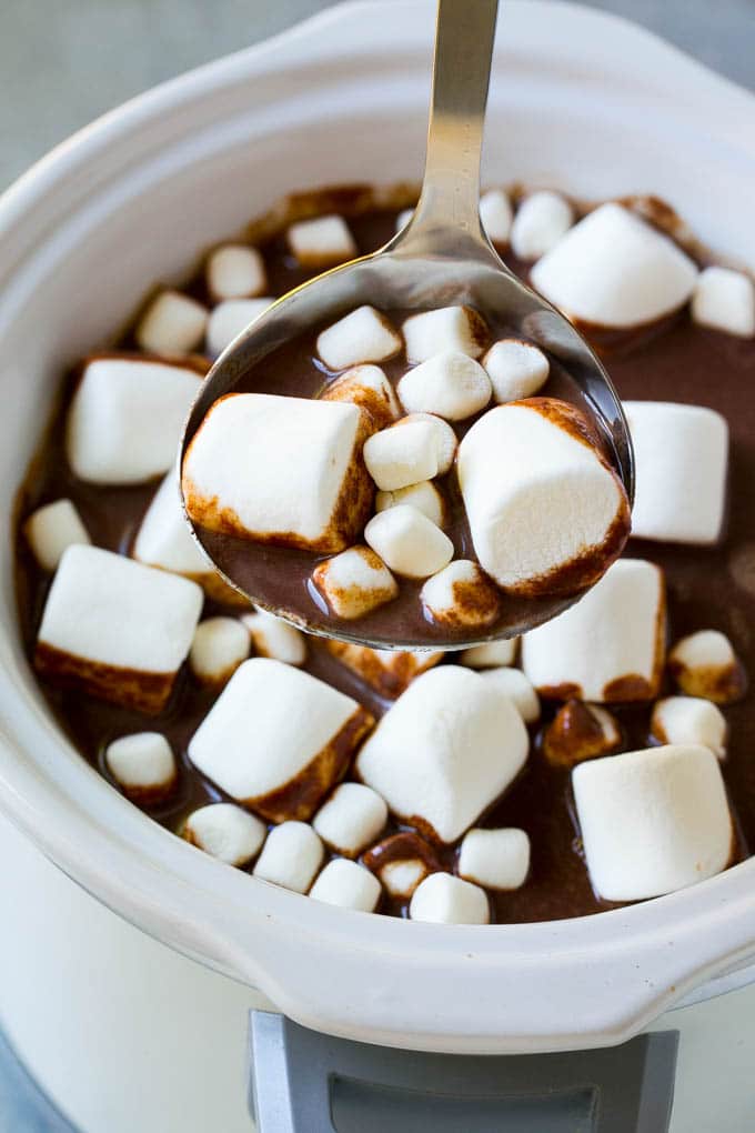 A ladle full of slow cooker hot chocolate topped with marshmallows.