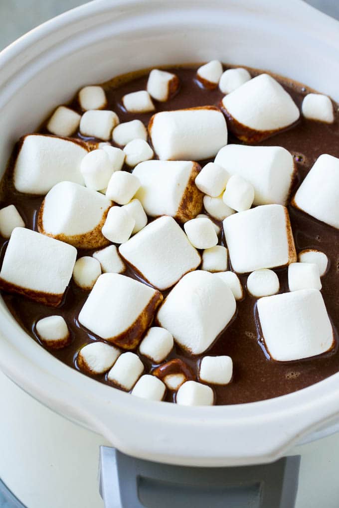 Slow cooker hot chocolate topped with an assortment of marshmallows.