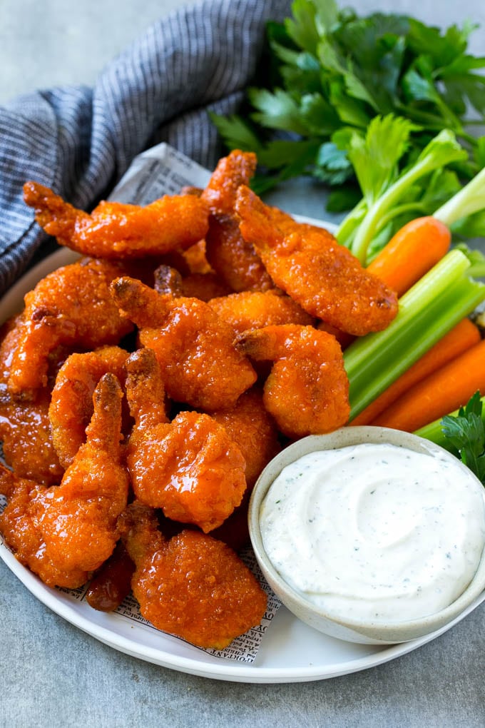 A platter of buffalo shrimp with carrots, celery and ranch dip.