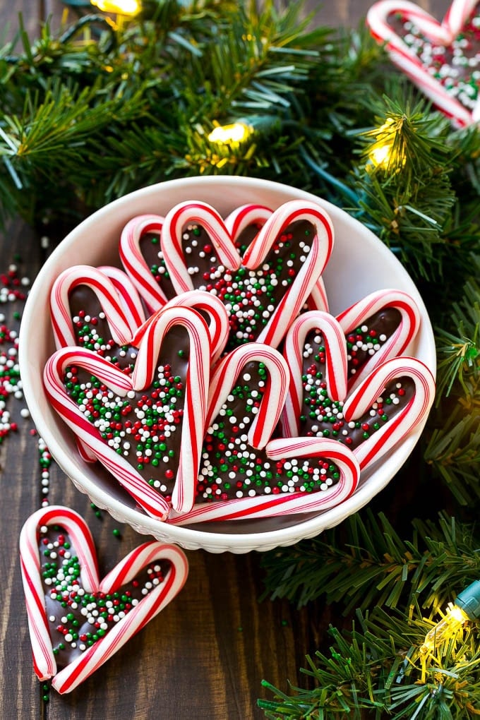 A bowl of candy cane hearts topped with festive sprinkles.