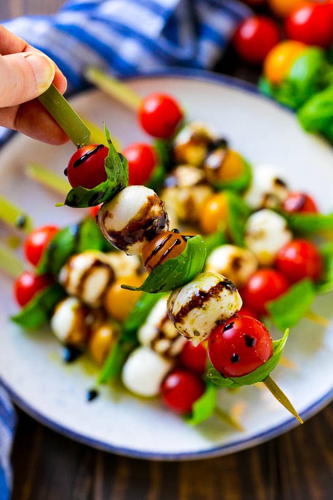 A kabob of mozzarella, tomatoes and basil drizzled with balsamic glaze.