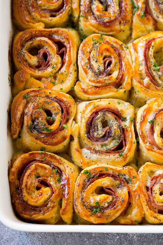 Ham and cheese pinwheels in a baking dish topped with parsley.