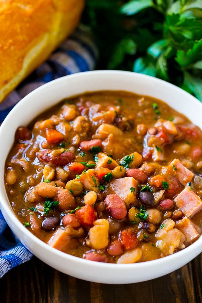 Slow Cooker Ham Bone Soup | Ham and Bean Soup | Ham Bone and Bean Soup | Ham Soup | Leftover Ham Recipe #ham #hamsoup #leftoverham #soup #slowcooker #crockpot #dinneratthezoo Crock pot ham bone soup in a bowl topped with parsley.