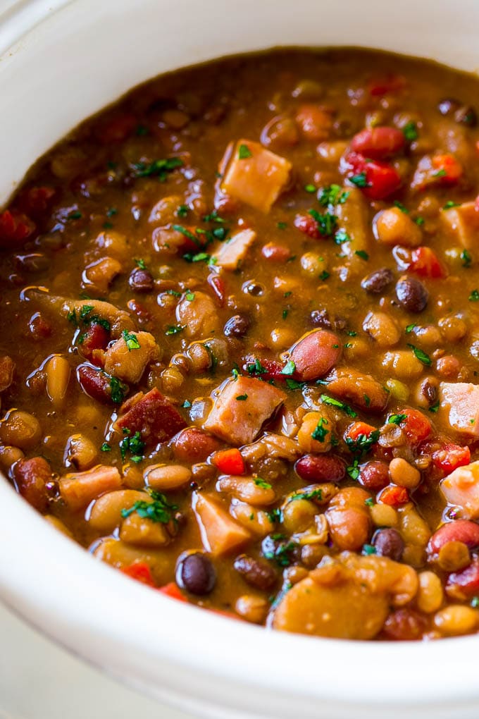 A slow cooker full of soup with parsley on top.