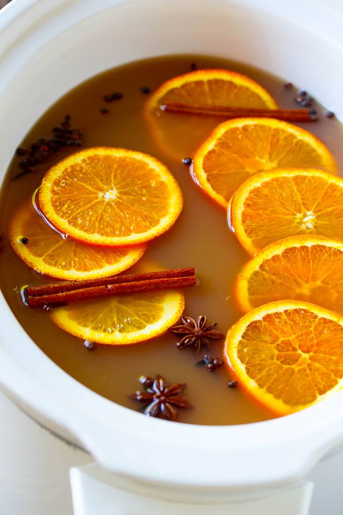 Crock pot spiced drink with orange slices and aromatic spices.