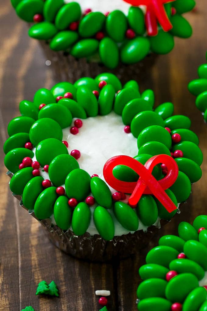 Wreath Christmas cupcakes are vanilla cakes topped with candy to make a festive dessert.