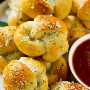 These easy garlic knots are smothered in butter, garlic, herbs and parmesan and are baked to golden brown perfection. A quick side dish for any meal!