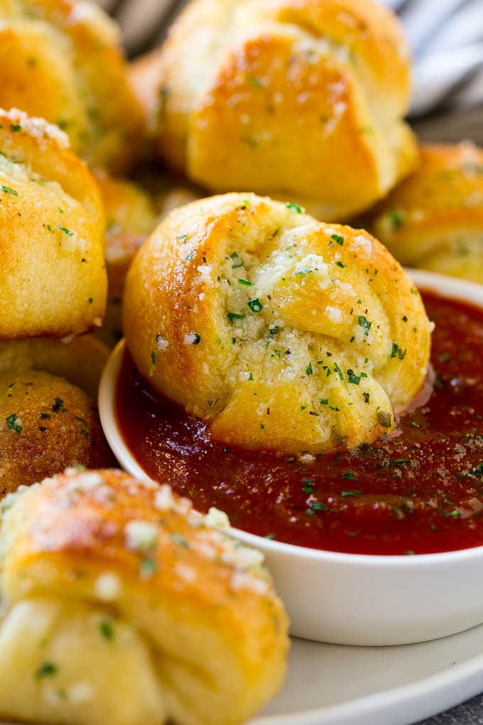 A garlic roll being dipped into marinara sauce for a delicious finishing touch.