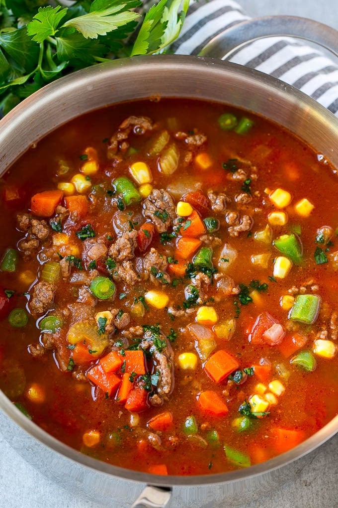 A pot of hamburger soup filled with cooked ground beef, veggies and seasonings.