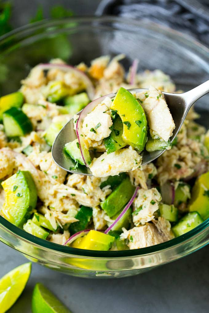 A spoon holding up a serving of tuna avocado salad.