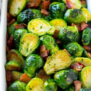 A dish of bacon roasted brussels sprouts with parsley.