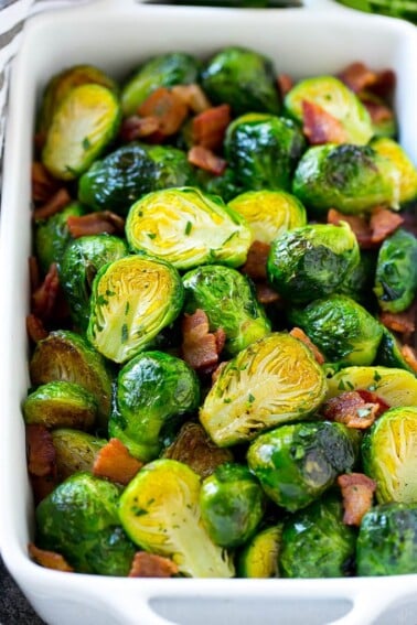 A dish of bacon roasted brussels sprouts with parsley.