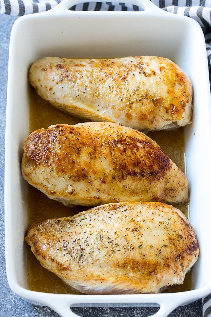 Chicken breasts coated in a lemon butter sauce in a baking dish.