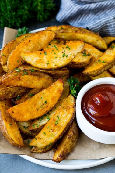 Baked potato wedges on a serving plate with a side of ketchup.