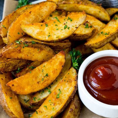 Baked potato wedges on a serving plate with a side of ketchup.