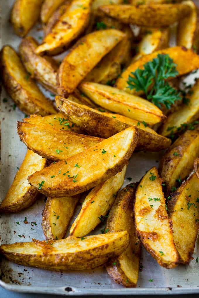 Baked potato wedges on a sheet pan, garnished with fresh parsley.