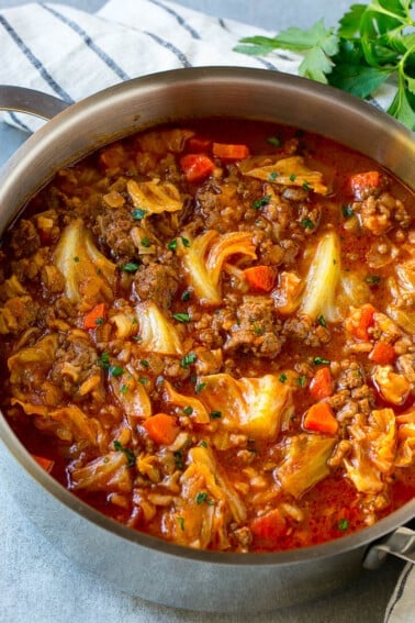 A pot full of cabbage roll soup garnished with parsley.