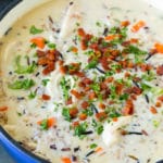 A pot of creamy chicken and wild rice soup with vegetables and bacon.