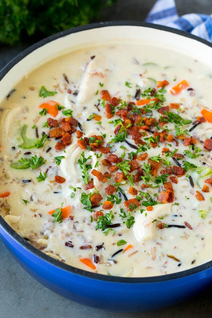 A pot of creamy chicken and wild rice soup with vegetables and bacon.