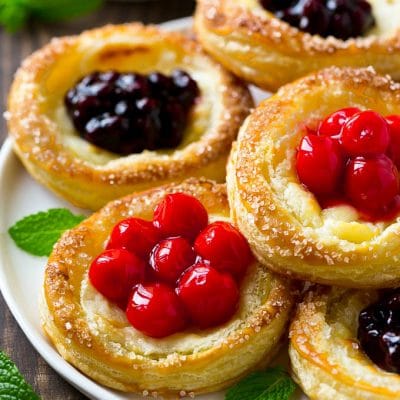A platter of cream cheese danish topped with fruit.