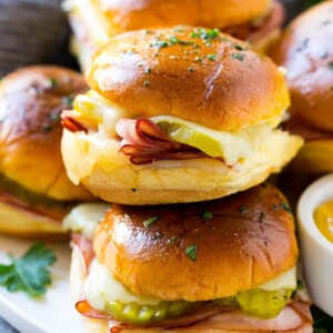 A pile of cuban sliders filled with ham, cheese and pickles.
