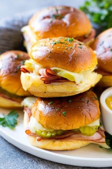 A pile of cuban sliders filled with ham, cheese and pickles.