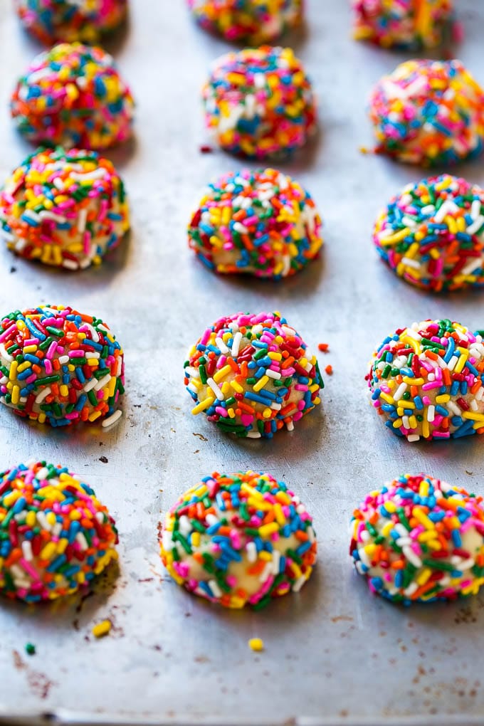 Balls of funfetti cookie dough coated in sprinkles.