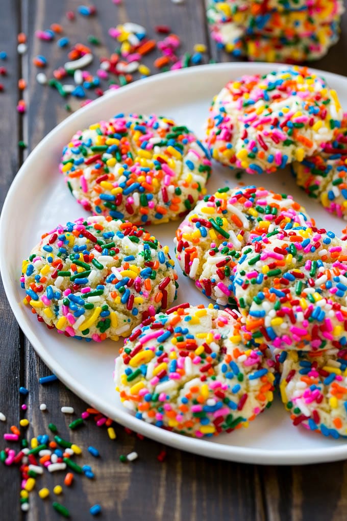 A plate of funfetti cookies coverd in rainbow sprinkles.