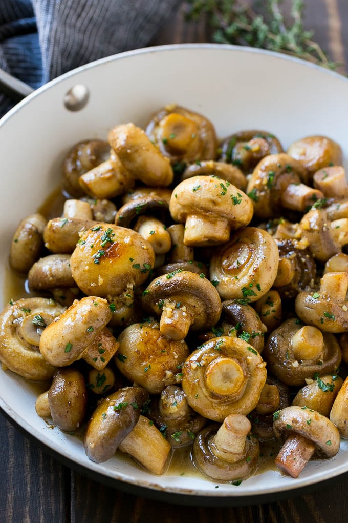 A pan full of cooked mushrooms coated in garlic butter.