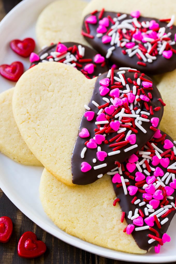 Heart sugar cookies dipped partway into dark chocolate and coated with Valentine's Day sprinkles.