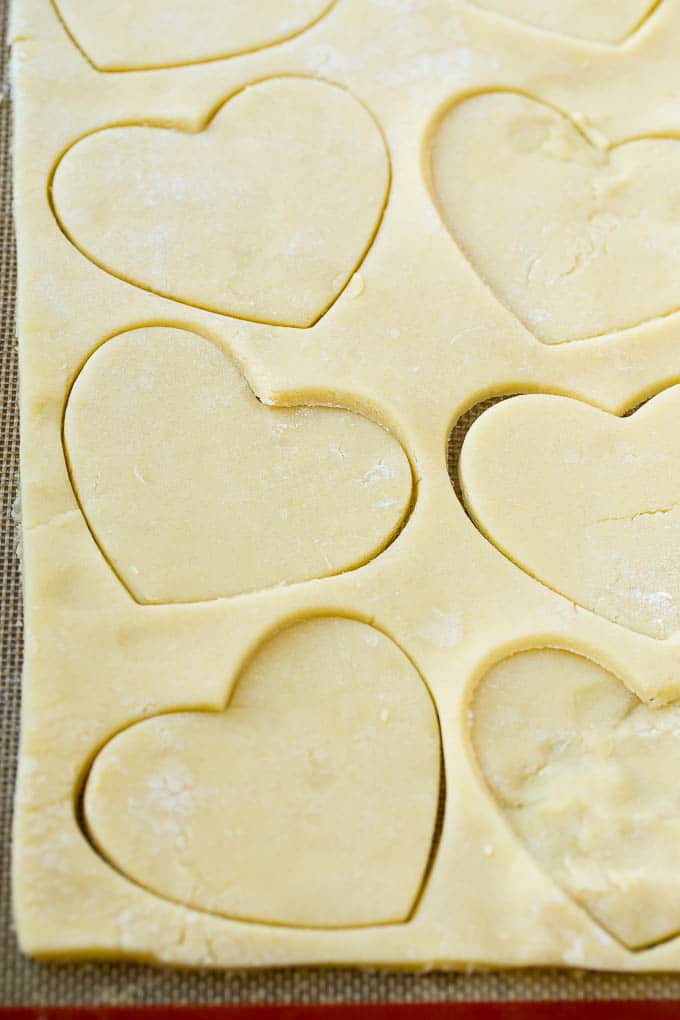 A sheet of sugar cookie dough with heart shaped cut outs.