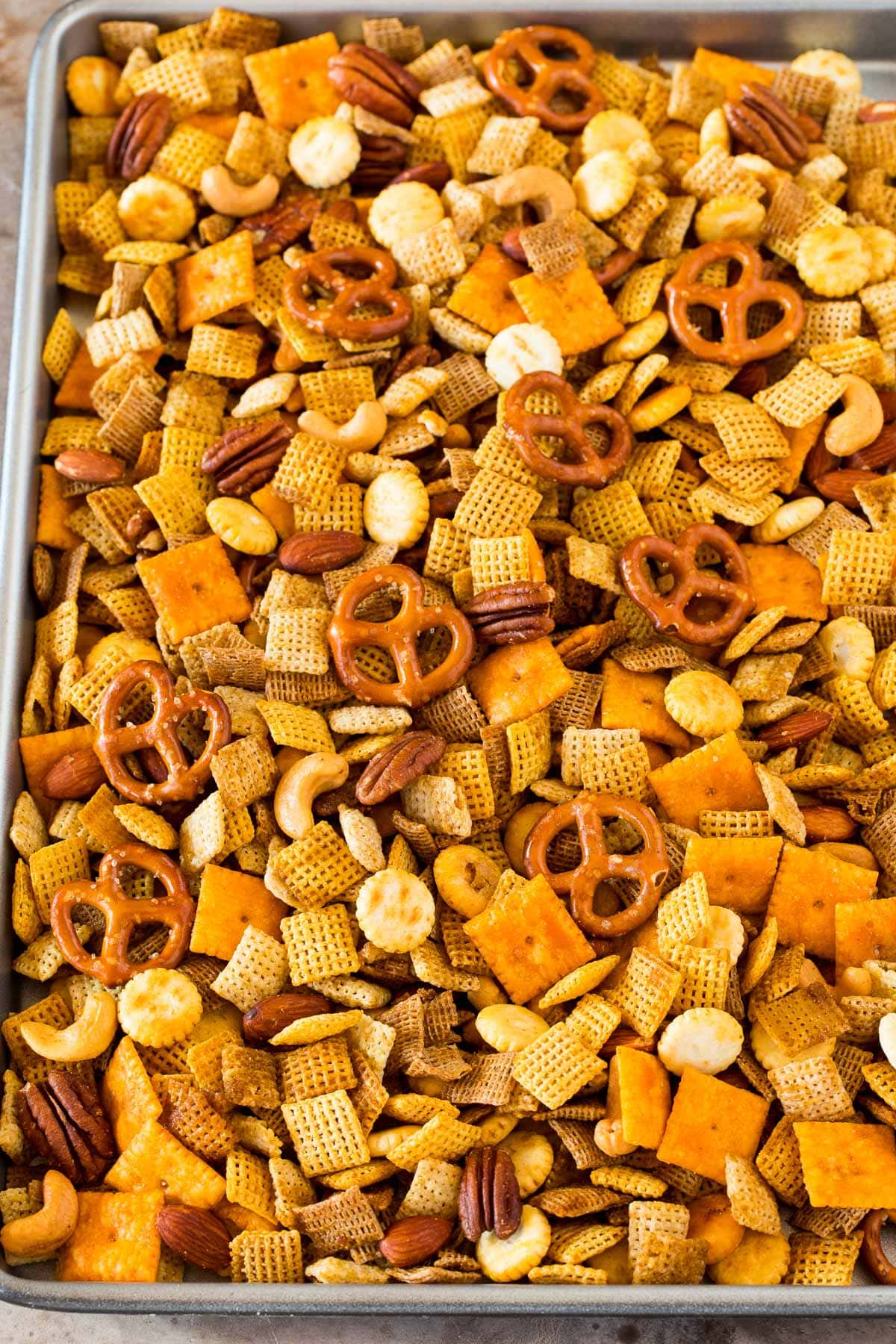 A sheet pan of Chex mix made with cereal, crackers, pretzels and nuts.