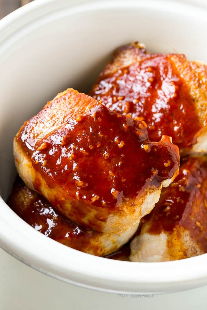 Browned pork chops in honey garlic sauce inside a crock pot.