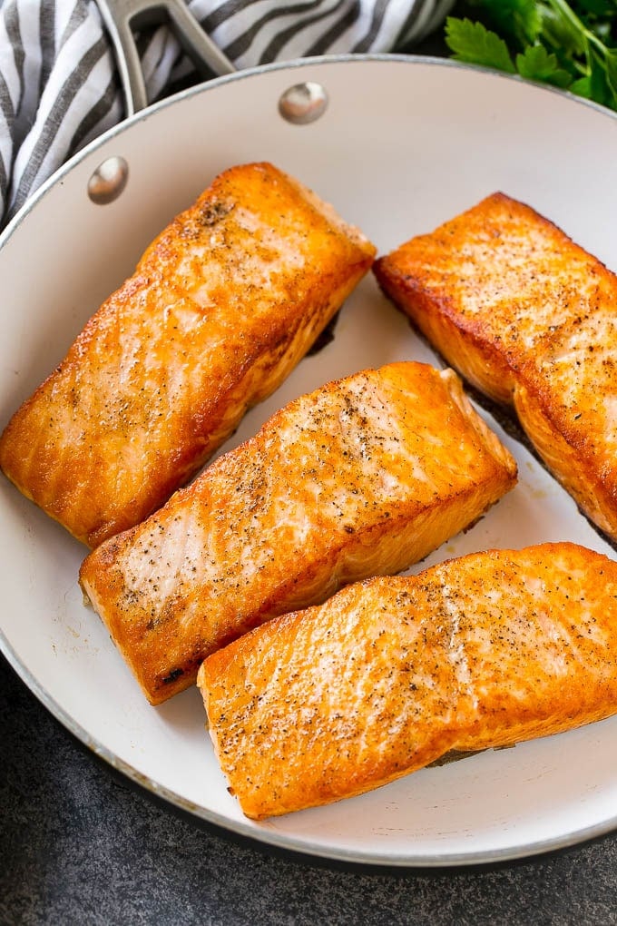 Seared salmon fillets in a frying pan.