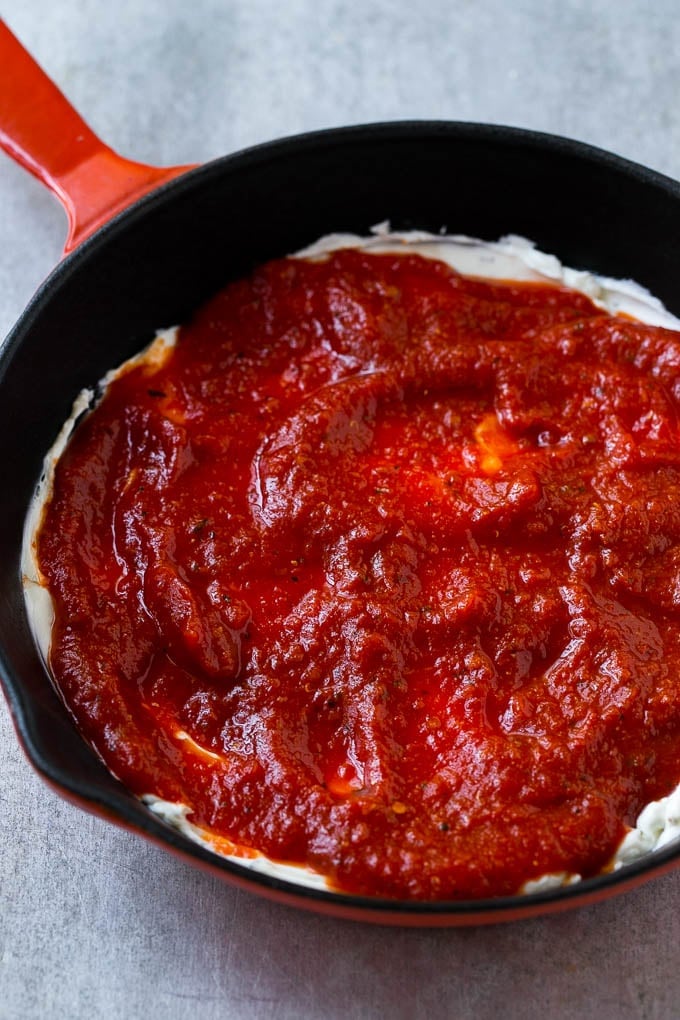 A layer of cream cheese topped with marinara sauce.