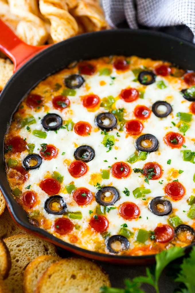 Pizza dip topped with pepperoni, olives and green peppers, served in a skillet with