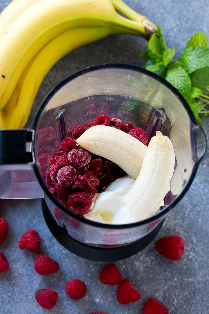 All of the ingredients for raspberry smoothies inside a blender.