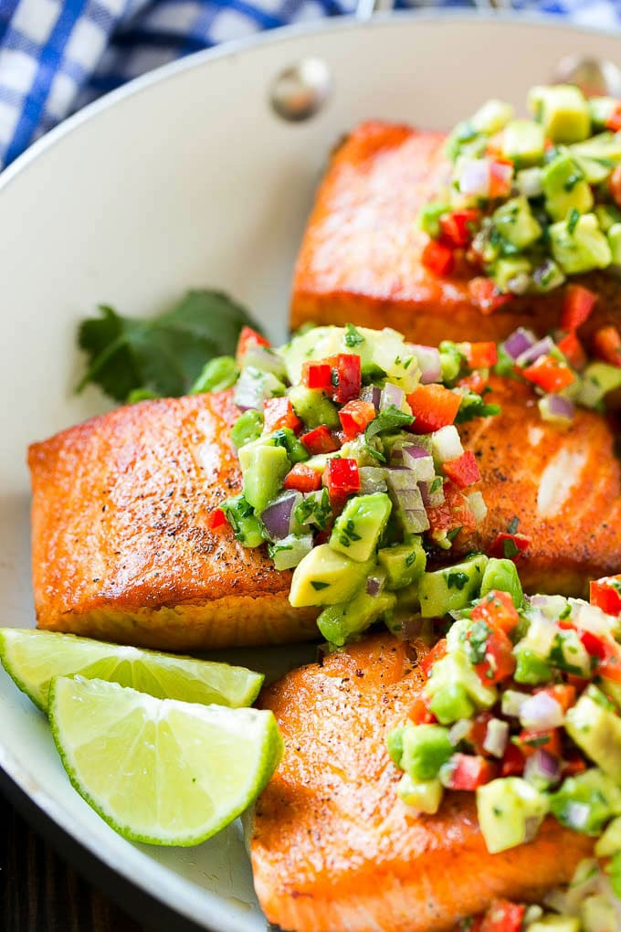 A pan of seared salmon with avocado salsa on top.