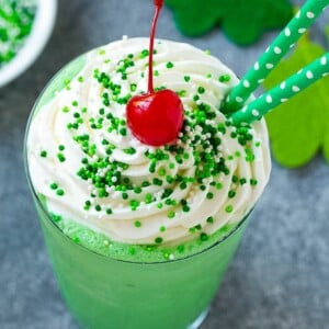 A mint Shamrock shake finished off with a swirl of whipped cream sprinkles and a cherry.
