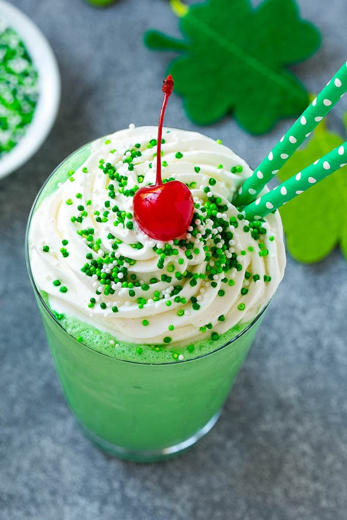 A mint Shamrock shake finished off with a swirl of whipped cream sprinkles and a cherry.