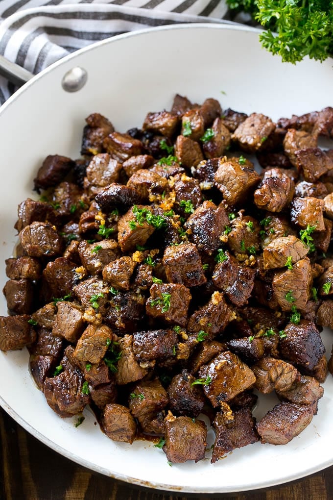 A frying pan of beef cubes tossed in garlic butter.