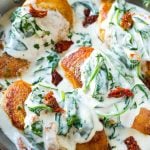 Sun dried tomato chicken covered in a creamy spinach sauce in a frying pan.